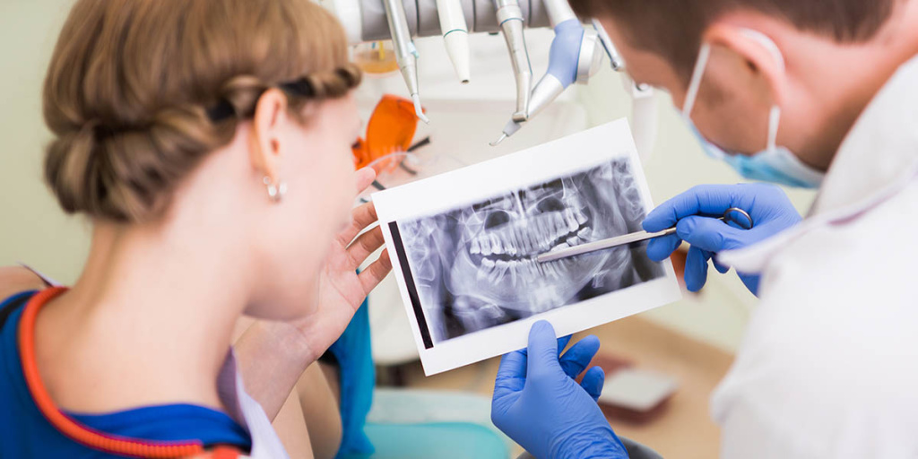 Стоматолог рассказывает пациенту о противопоказаниях к имплантации зубов